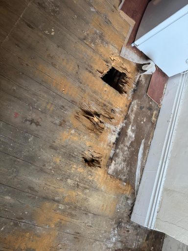 Damaged wooden floor with multiple holes and signs of wear.